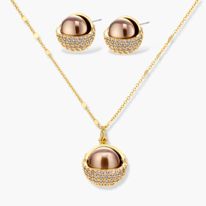 Elegant spherical pendant necklace and earrings set featuring crystal-pavé bottom half in gold or silver finish on white background.