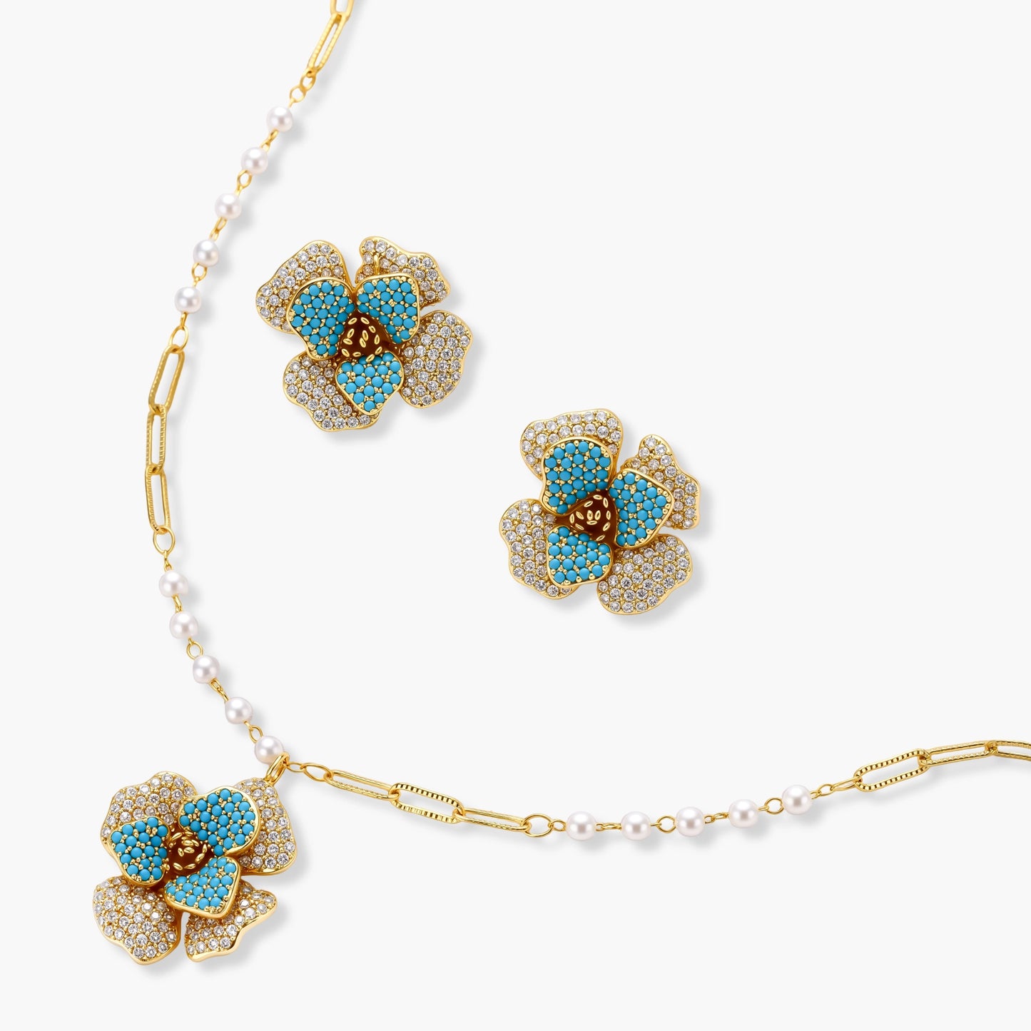 14K gold-plated floral jewelry set with blue cubic zirconia centers and pearl chain details on white background.