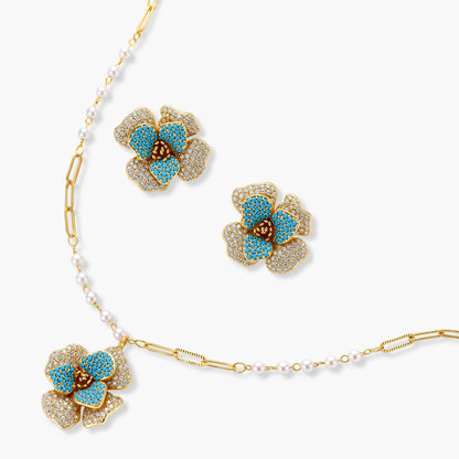 14K gold-plated floral jewelry set with blue cubic zirconia centers and pearl chain details on white background.