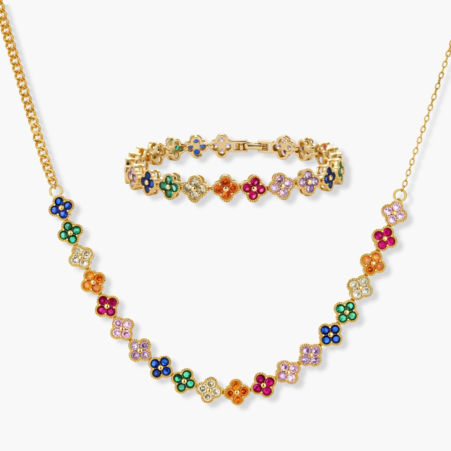 Colorful four-leaf clover jewelry set with rainbow cubic zirconia stones in gold-plated setting on white background