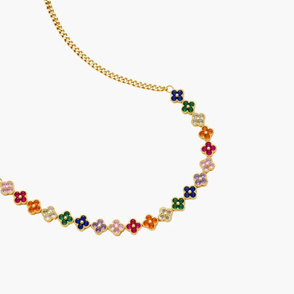 Colorful four-leaf clover jewelry set with rainbow cubic zirconia stones in gold-plated setting on white background