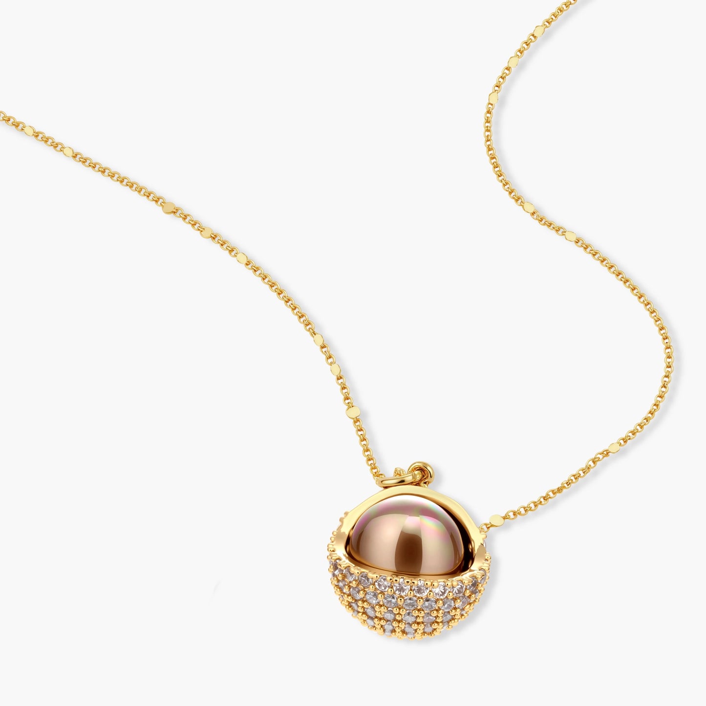 Elegant spherical pendant necklace and earrings set featuring crystal-pavé bottom half in gold or silver finish on white background.