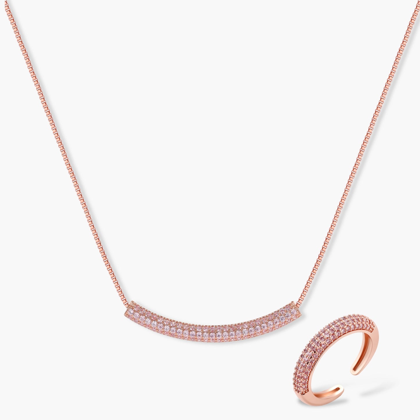 Rose gold jewelry set with pavé cubic zirconia stones including curved necklace, hoop earrings, and adjustable ring on cream background.