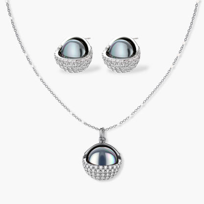 Elegant spherical pendant necklace and earrings set featuring crystal-pavé bottom half in gold or silver finish on white background.