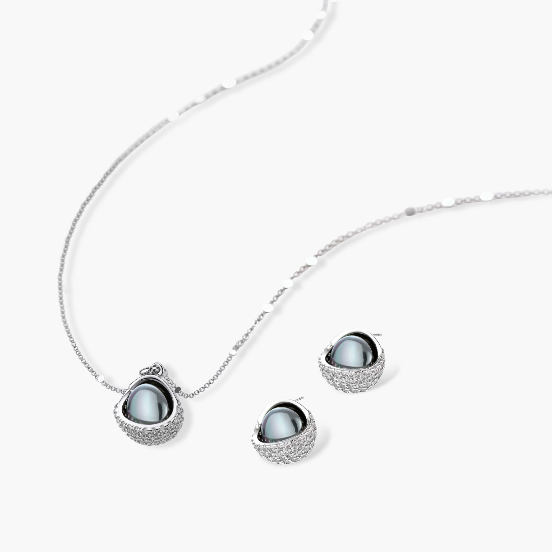 Elegant spherical pendant necklace and earrings set featuring crystal-pavé bottom half in gold or silver finish on white background.